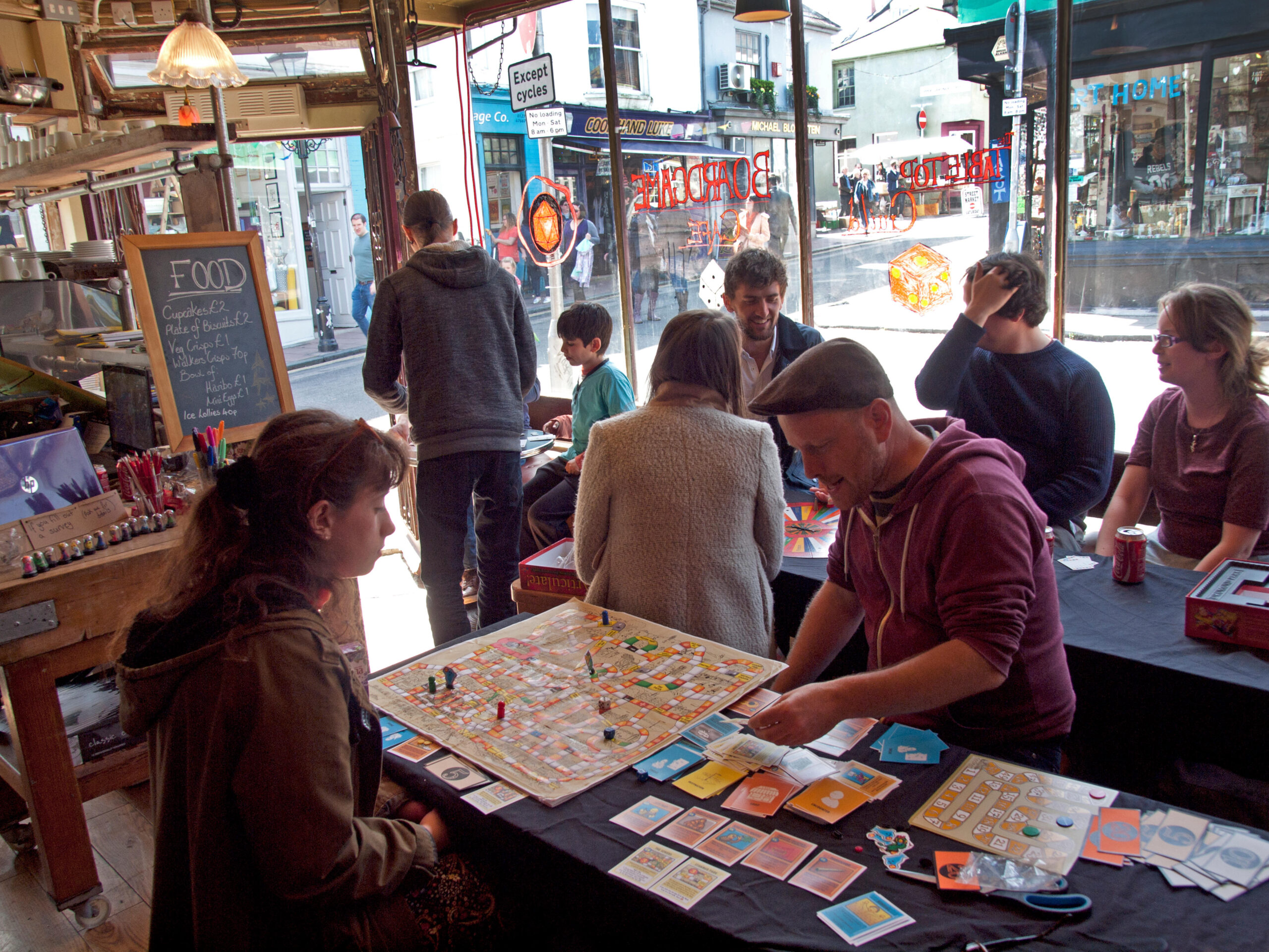 Two people in a cafe playing Wingspan on the table